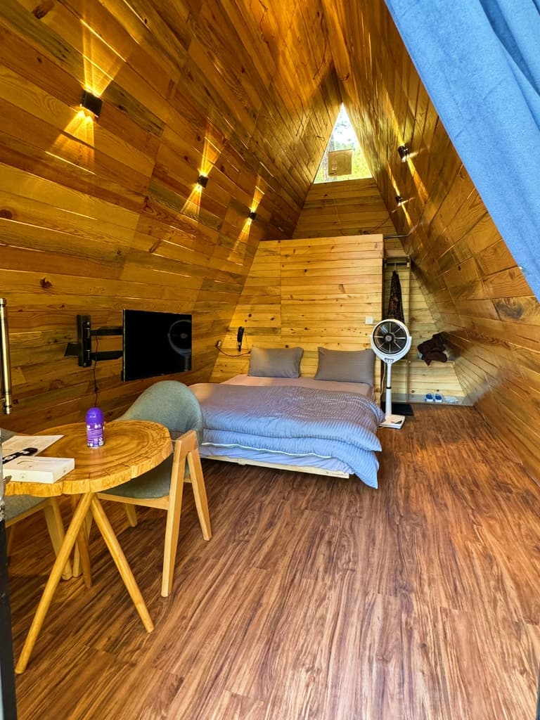 Cozy wooden hut with a geyser and a bed.